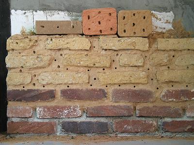 Pelzbienenwand neben einer Haust&uuml;r: Unten gebrannte, oben ungebrannte Lehmziegel